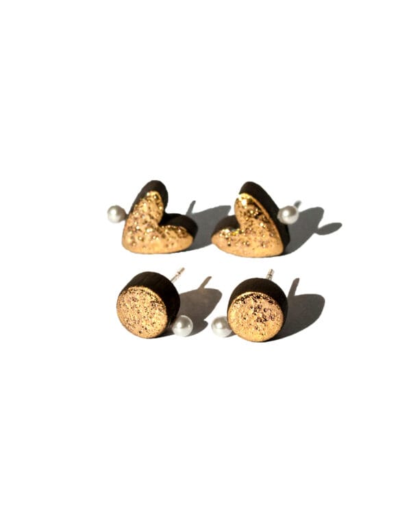 Handmade black earthenware stud earrings with moon-textured surface, gold luster, and a small white pearl