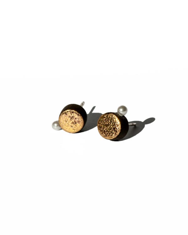 Handmade black earthenware stud earrings with moon-textured surface, gold luster, and a small white pearl