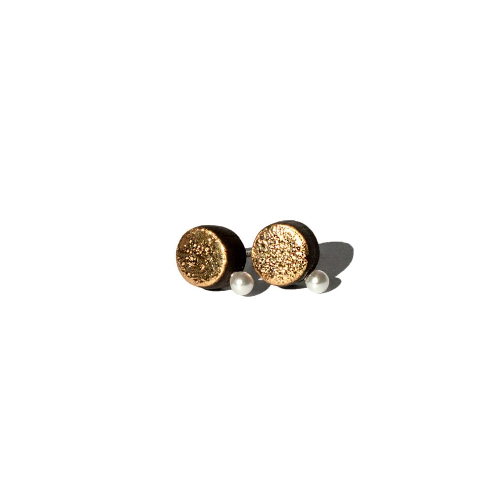 Handmade black earthenware stud earrings with moon-textured surface, gold luster, and a small white pearl