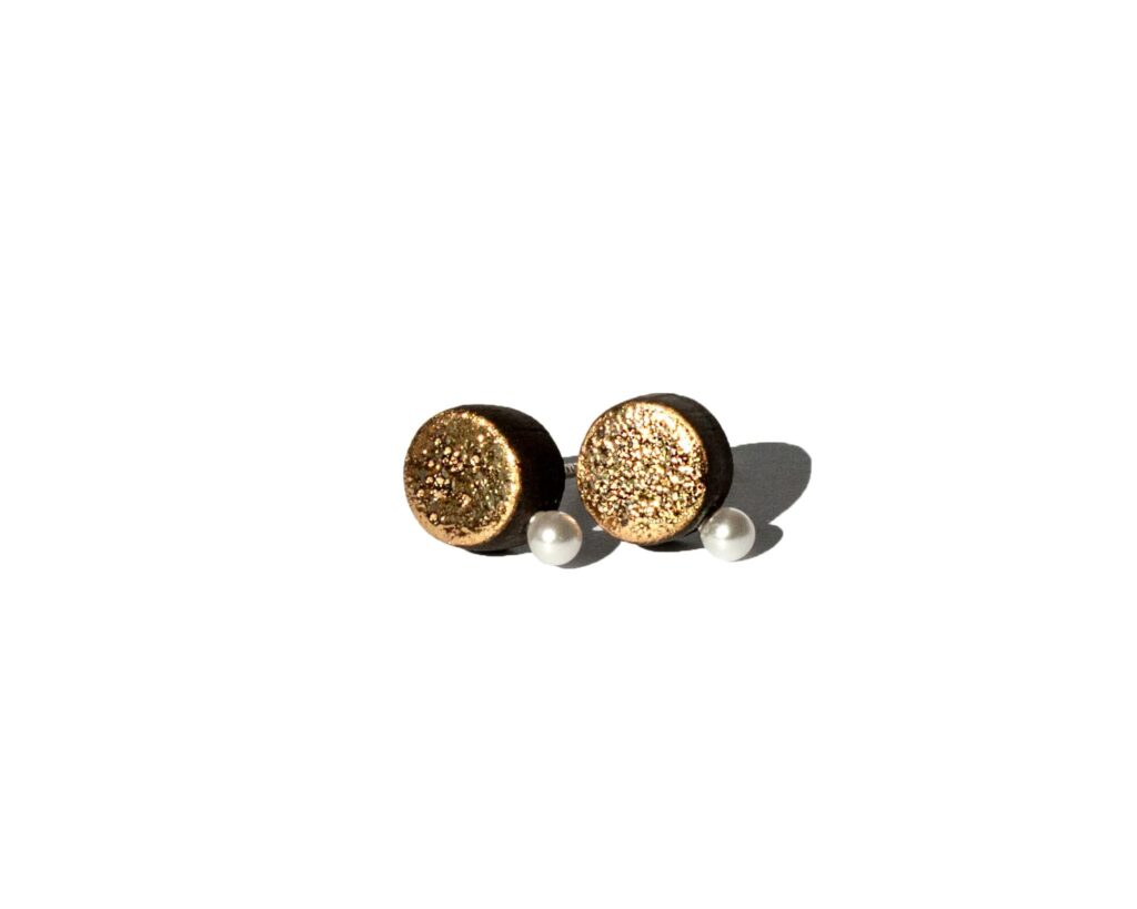 Handmade black earthenware stud earrings with moon-textured surface, gold luster, and a small white pearl