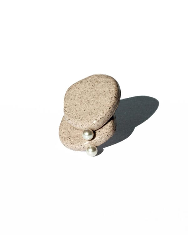 Minimalist ceramic stud earrings in light concrete-colored clay with cracked glaze and a small pearl accent