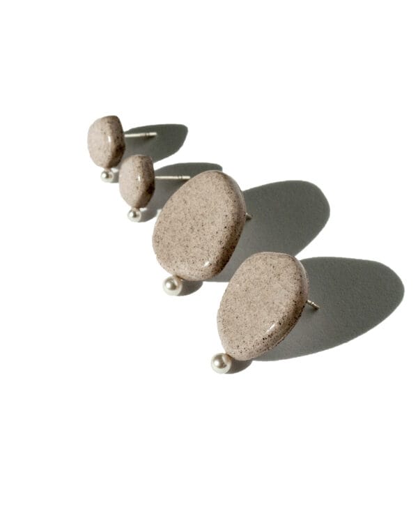 Minimalist ceramic stud earrings in light concrete-colored clay with cracked glaze and a small pearl accent