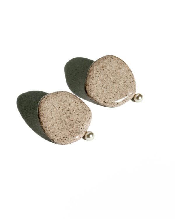 Minimalist ceramic stud earrings in light concrete-colored clay with cracked glaze and a small pearl accent