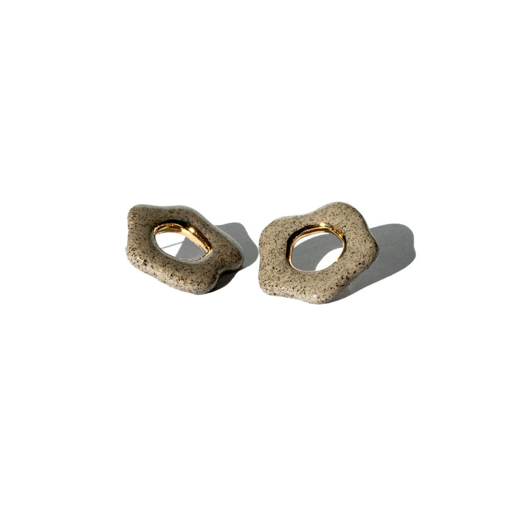 Minimalist ceramic flower stud earrings made from grey stoneware clay with a gold luster accent in the center