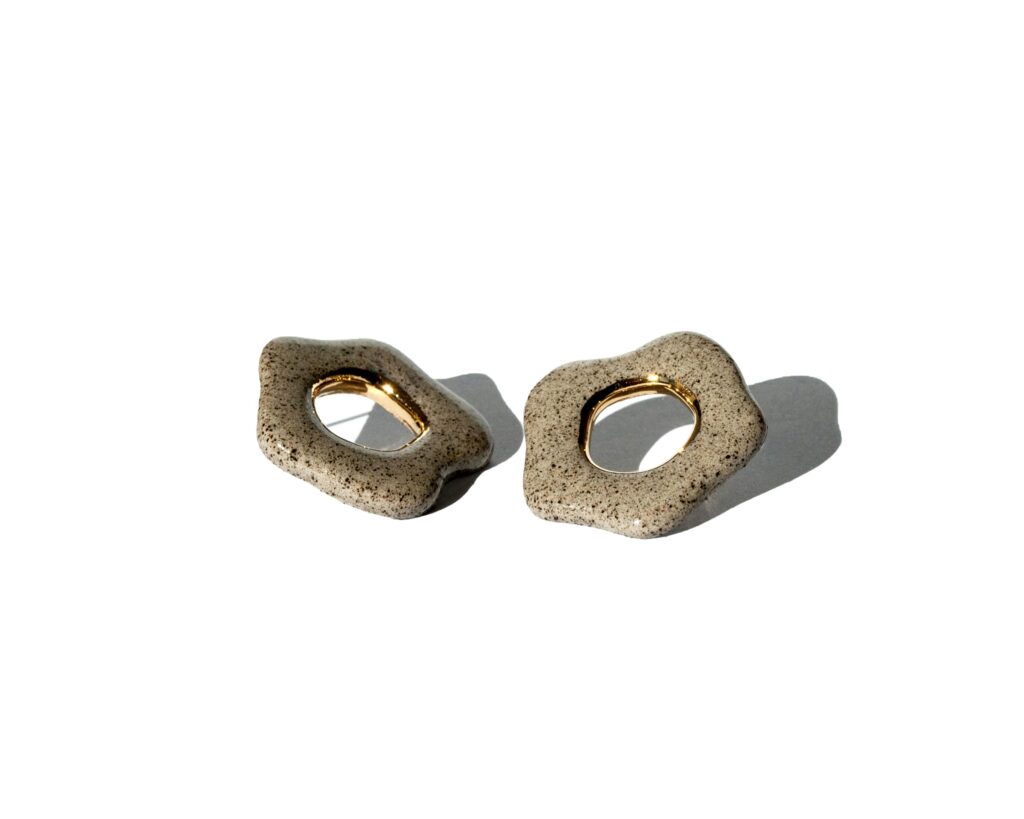 Minimalist ceramic flower stud earrings made from grey stoneware clay with a gold luster accent in the center