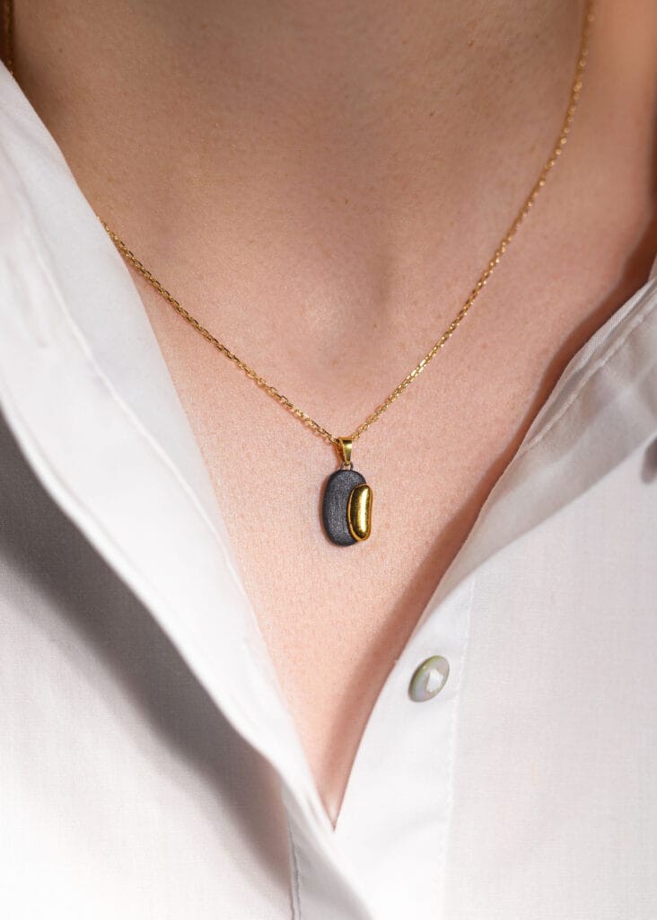 Handmade black porcelain pendant necklace with two-layer design, matte and glossy finishes, gold luster decoration, and gold-plated sterling silver chain and bail