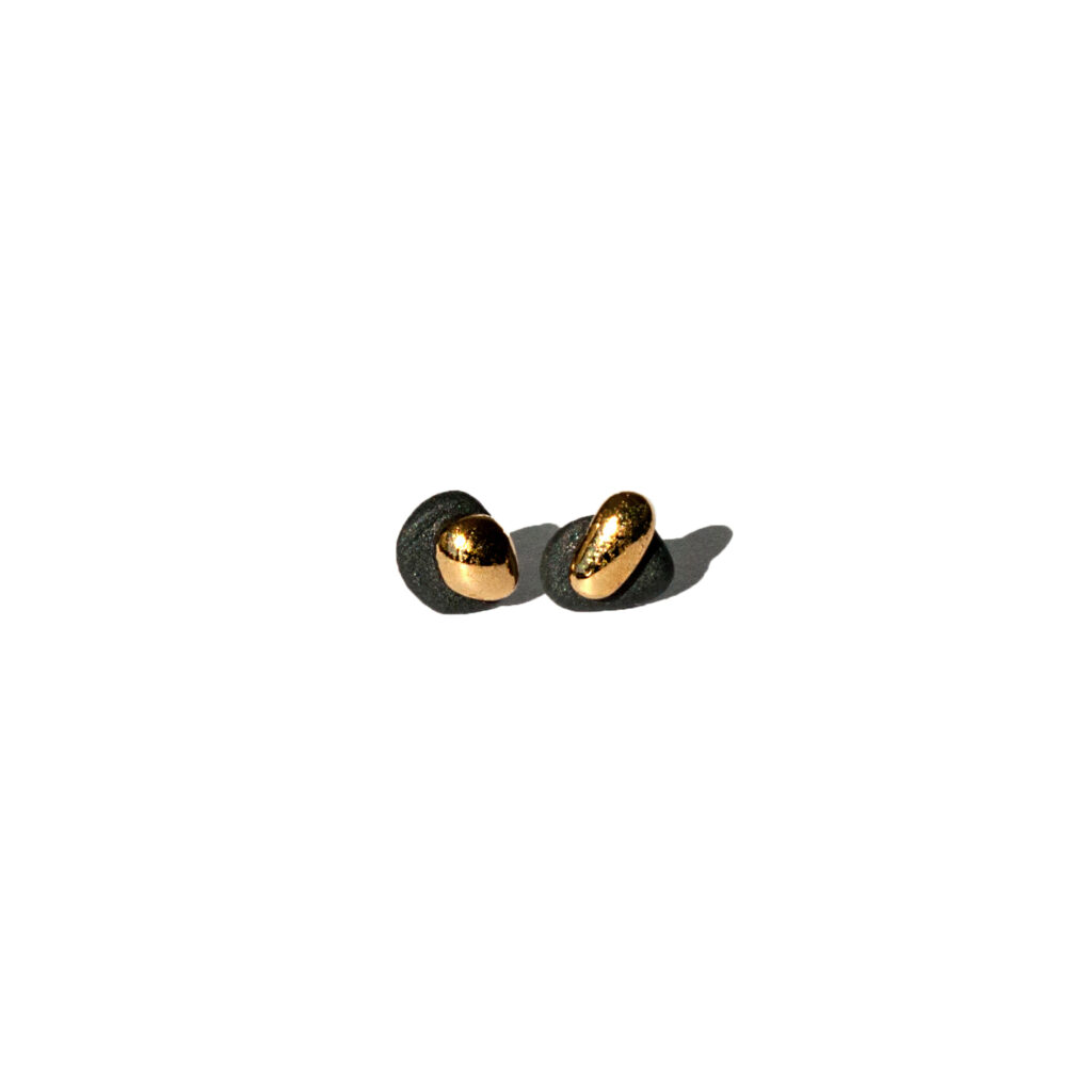 Handmade black porcelain stud earrings with asymmetrical rounded shapes, matte and glossy layers, gold luster accents, and sterling silver posts