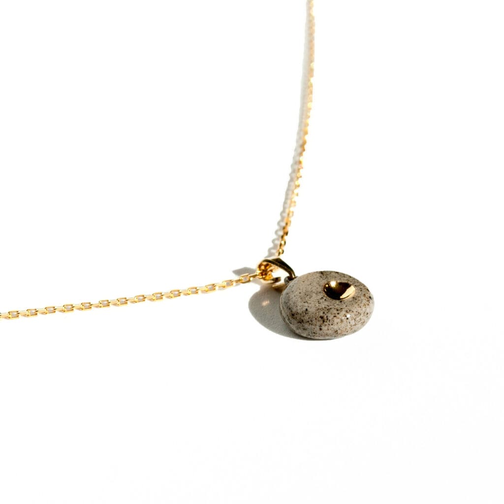 Handmade grey stoneware pendant necklace with black grog, round shape, clear glossy glaze, and hand-painted gold luster detail on gold-plated sterling silver chain