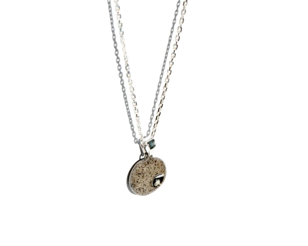 Handmade grey stoneware pendant necklace with black grog, round shape, clear glossy glaze, hand-painted platinum dimple detail, on sterling silver chain and bail