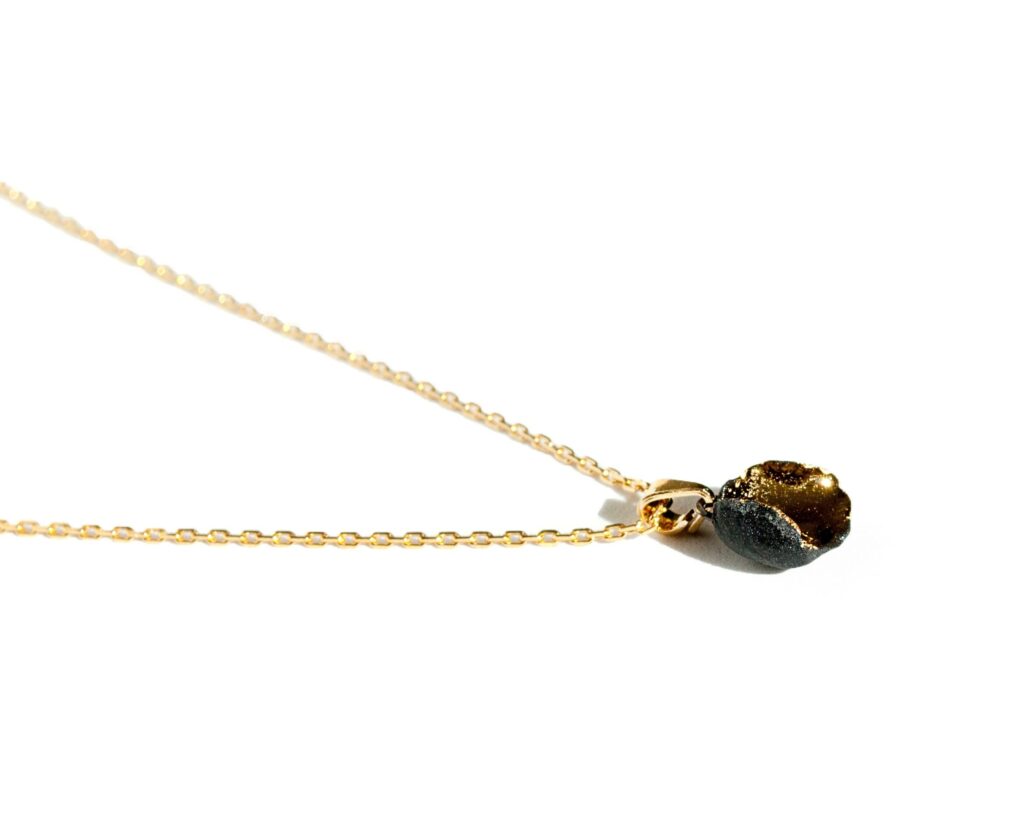 Handmade irregular black porcelain pendant necklace with matte unglazed exterior, glossy inner glaze, and 24k gold luster, on a gold-plated sterling silver chain