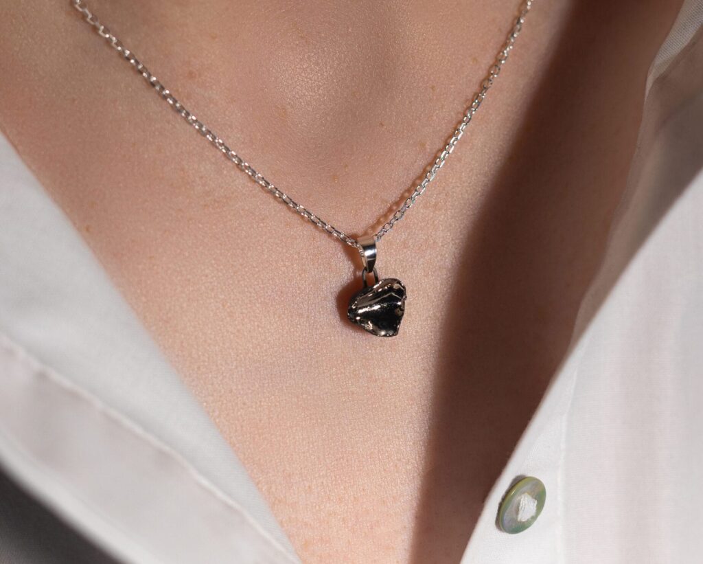 Handmade irregular black porcelain pendant necklace with matte unglazed exterior, glossy inner glaze, and platinum luster, on a sterling silver chain