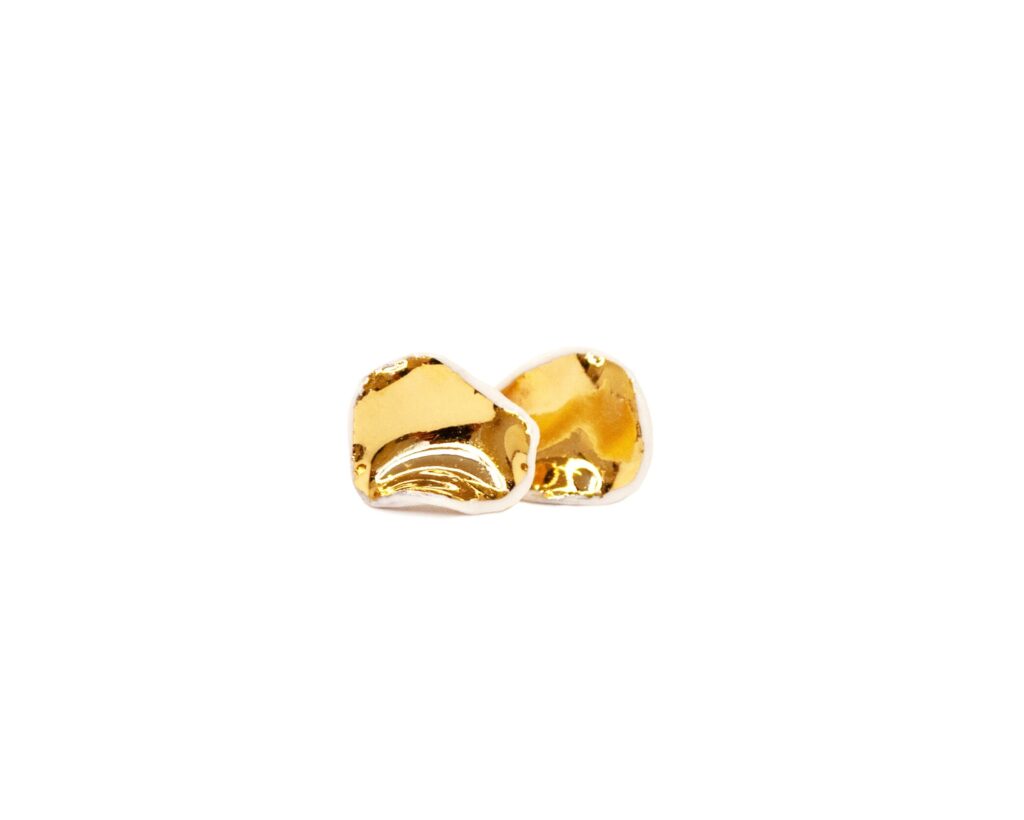 White Matter Small handmade white porcelain stud earrings with gold luster finish, organic irregular shape, front view, minimalist ceramic jewelry made in Lithuania