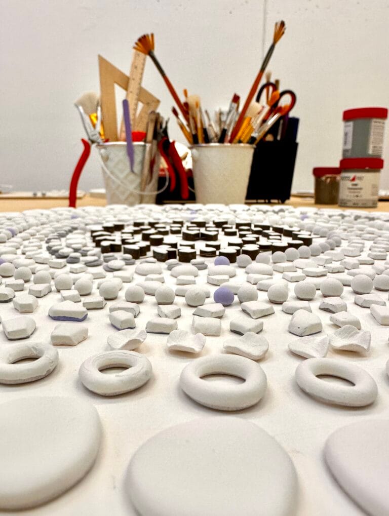 Handmade ceramic jewelry pieces arranged on the studio table before glazing and firing