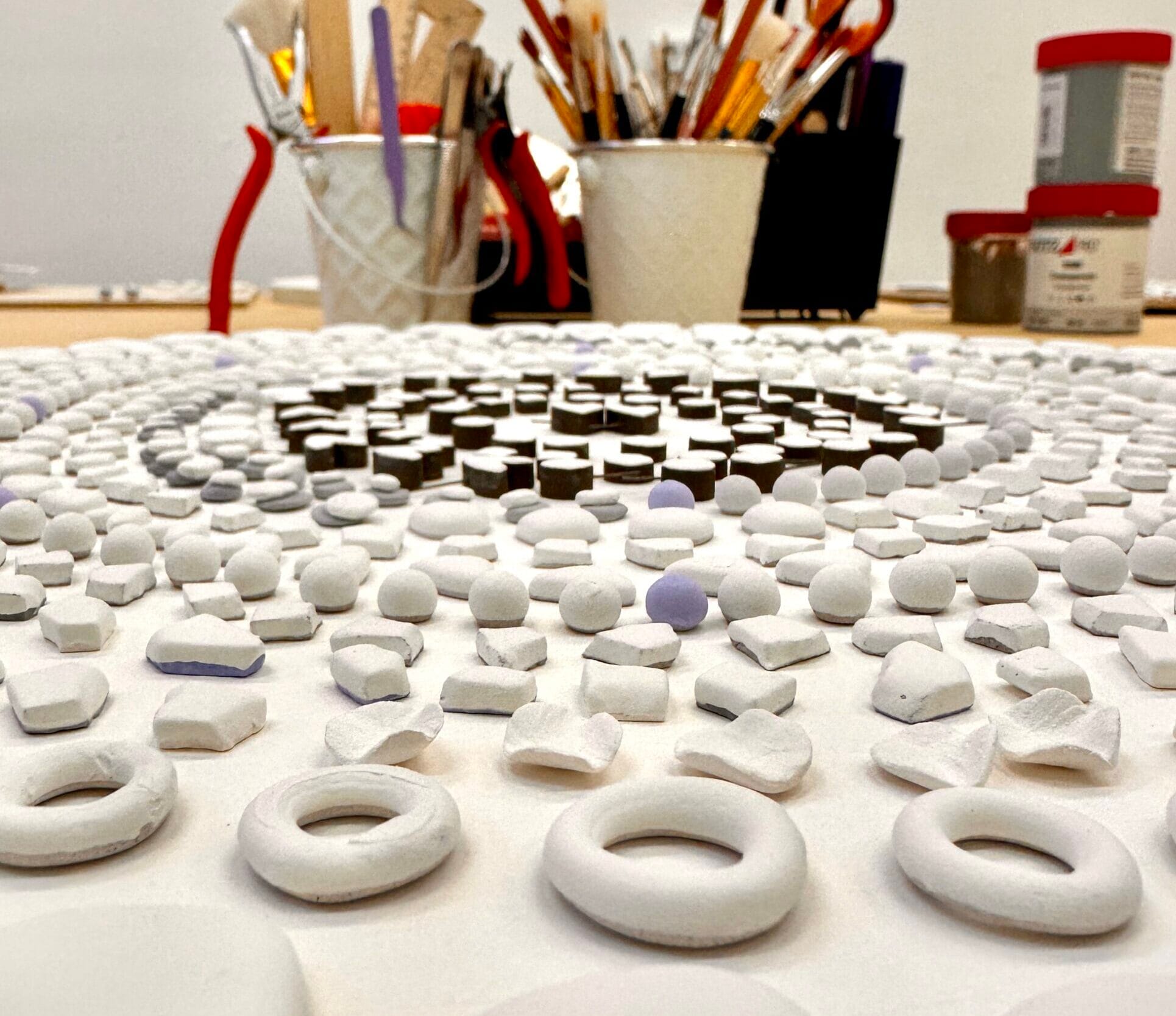 Handmade ceramic jewelry pieces arranged on the studio table before glazing and firing