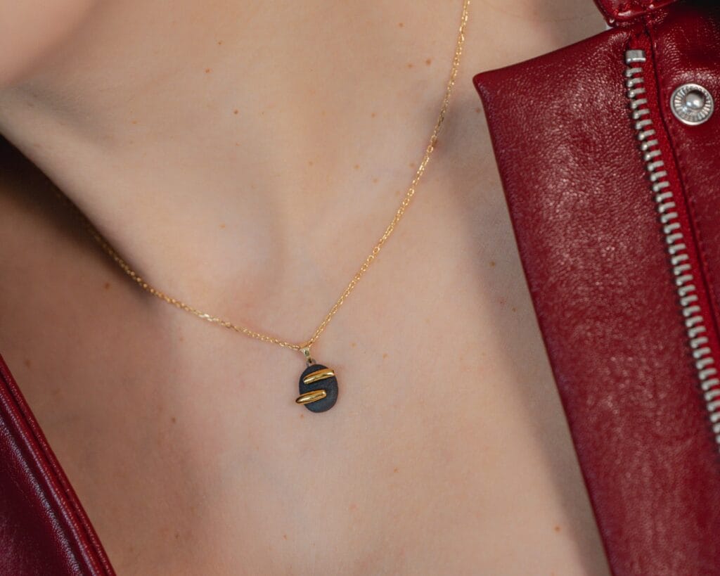 Black Balance handmade black porcelain necklace with gold luster worn by a model, close-up view