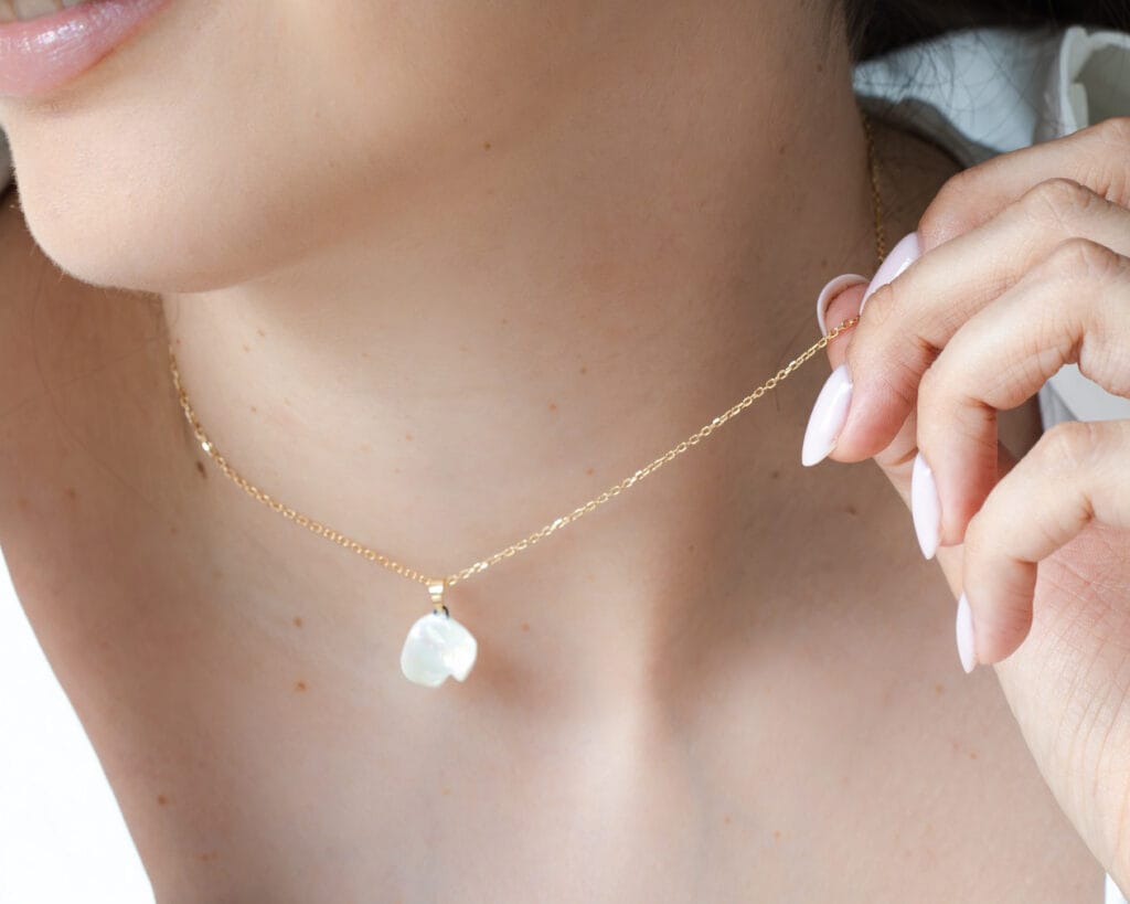 Flower Petal handmade white porcelain necklace with mother of pearl luster held by a model, close-up view