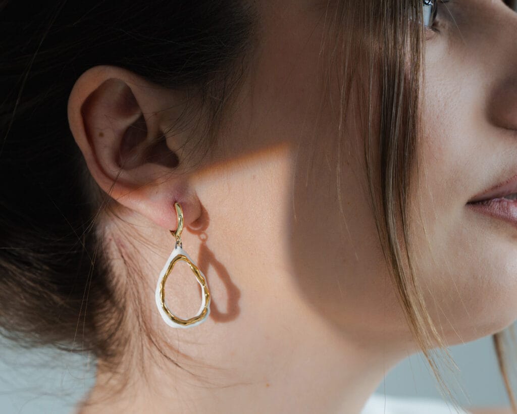 White Drop handmade white porcelain drop earrings with gold-plated hoops and gold luster, close detail
