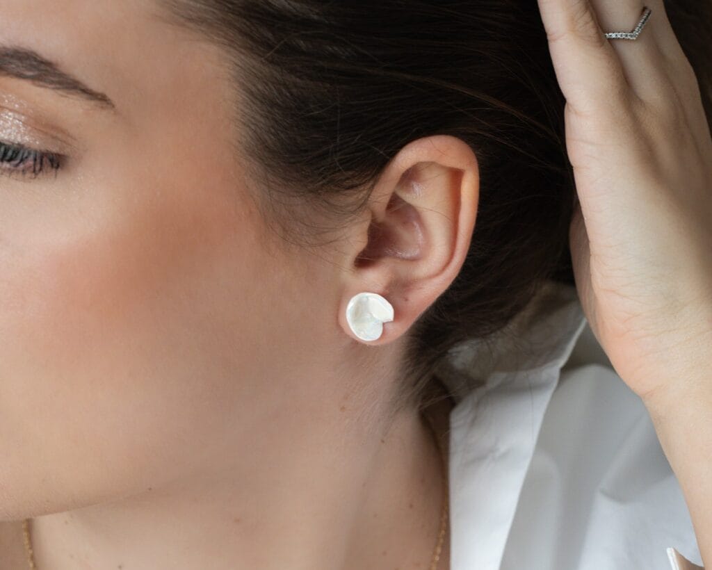 White Petal handmade white porcelain stud earrings and matching pendant worn as a jewelry set, close-up