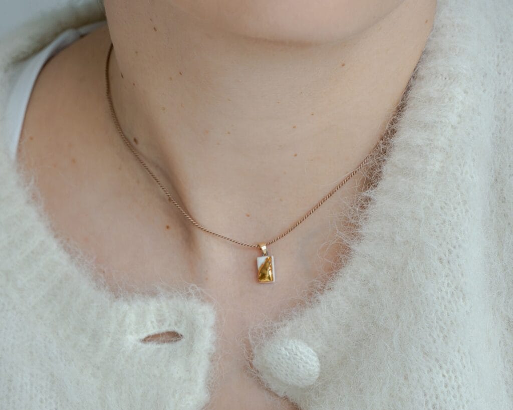 White Relief handmade white porcelain pendant necklace with gold luster relief details, close-up