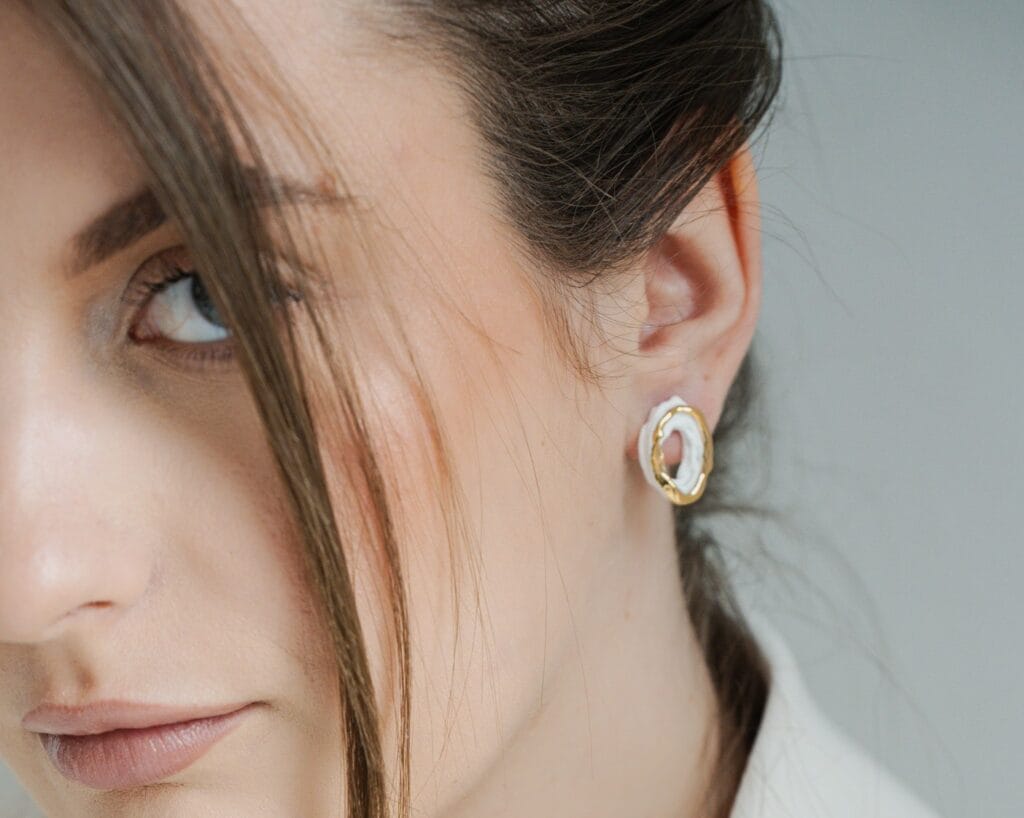 White Ripple handmade white porcelain earrings worn on ear, portrait view