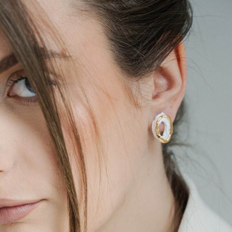 White Ripple handmade white porcelain earrings worn on ear, portrait view