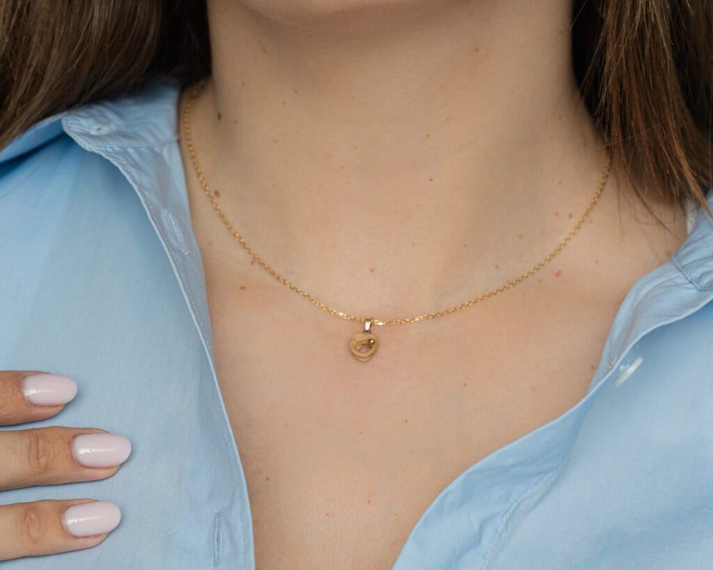 Nude Spring handmade nude porcelain necklace with gold luster bud and gold-plated silver chain worn by a model, close-up view